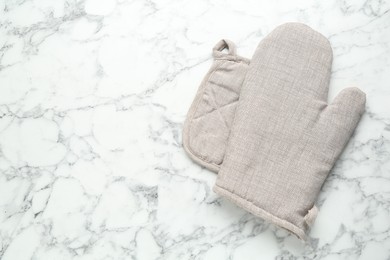 Photo of Oven glove and potholder on white marble table, flat lay. Space for text
