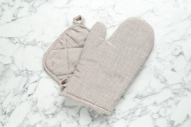 Photo of Oven glove and potholder on white marble table, flat lay