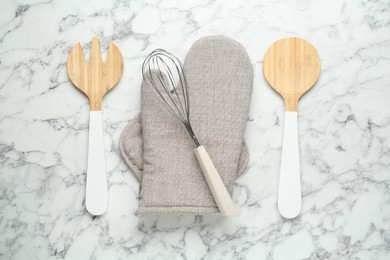 Photo of Oven glove, potholder and other kitchen utensils on white marble table, flat lay