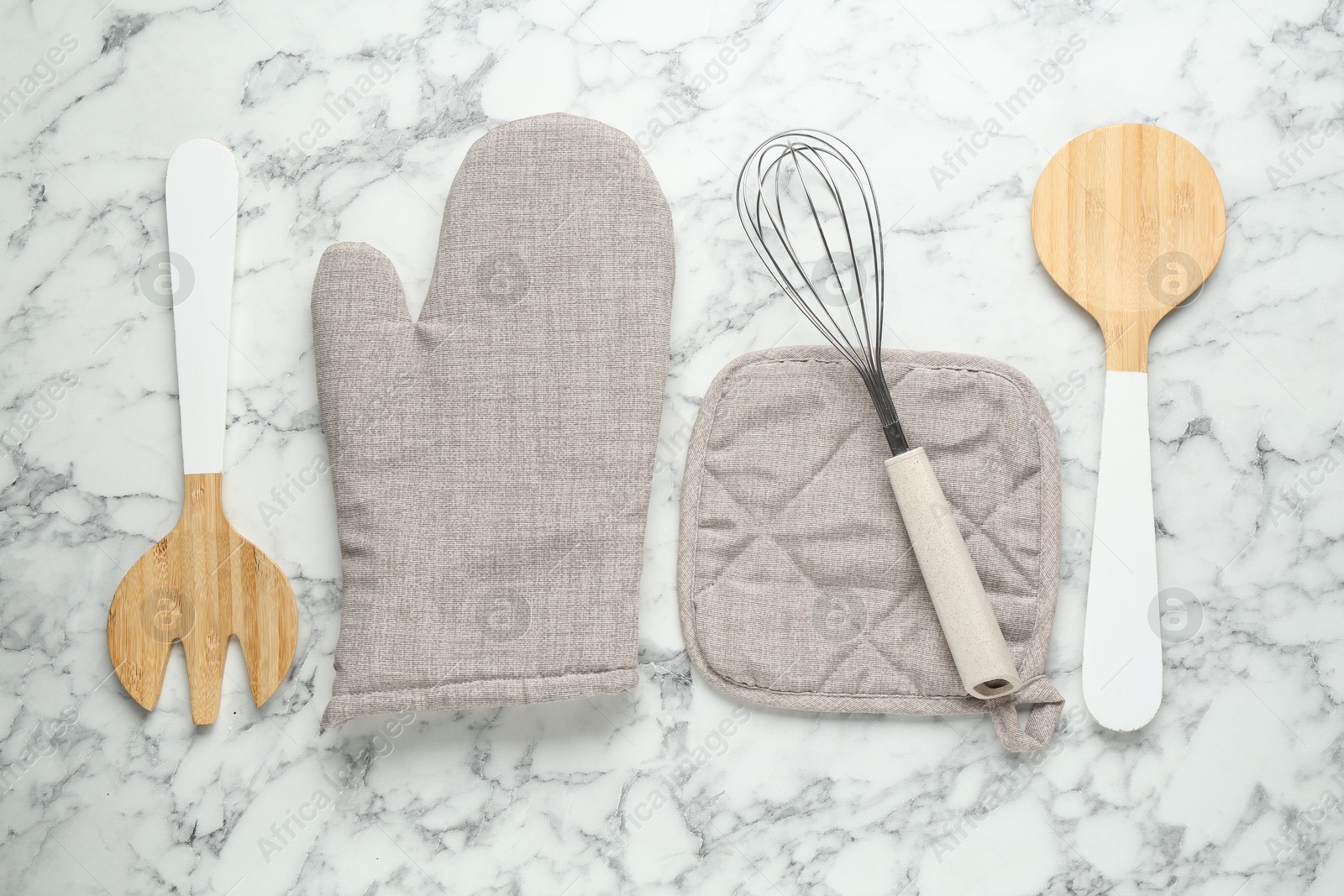 Oven glove, potholder and other kitchen utensils on white marble table, flat lay Photo of Oven glove, potholder and other kitchen utensils on white marble table, flat lay
