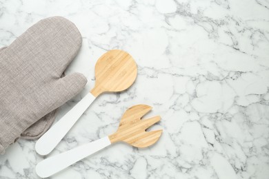 Photo of Oven glove, potholder and other kitchen utensils on white marble table, flat lay. Space for text
