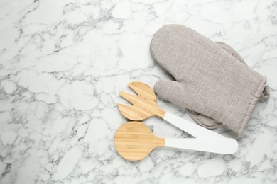 Photo of Oven glove, potholder and other kitchen utensils on white marble table, flat lay. Space for text