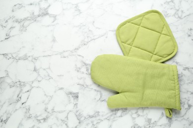 Photo of Oven glove and potholder on white marble table, flat lay. Space for text