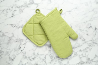 Photo of Oven glove and potholder on white marble table, flat lay