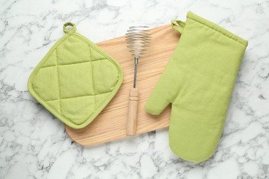 Photo of Oven glove, potholder and other kitchen utensils on white marble table, flat lay
