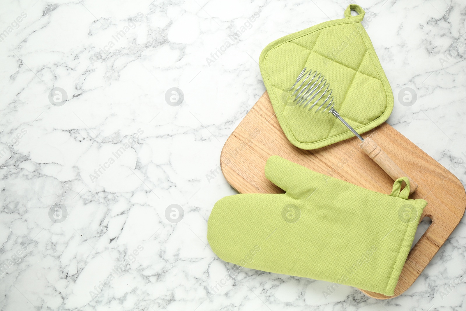 Photo of Oven glove, potholder and other kitchen utensils on white marble table, flat lay. Space for text