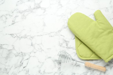 Photo of Oven glove, potholder and whisk on white marble table, flat lay. Space for text