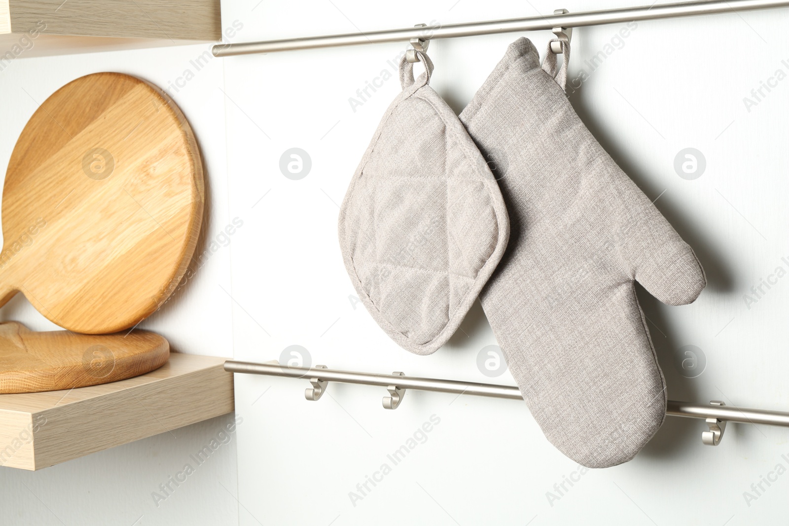 Photo of Oven glove and potholder hanging on metal rack in kitchen