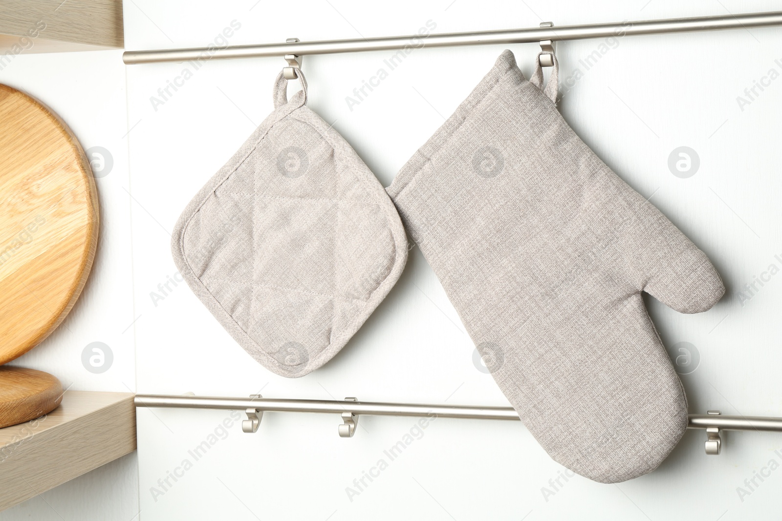 Photo of Oven glove and potholder hanging on metal rack in kitchen