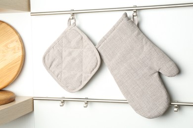 Photo of Oven glove and potholder hanging on metal rack in kitchen