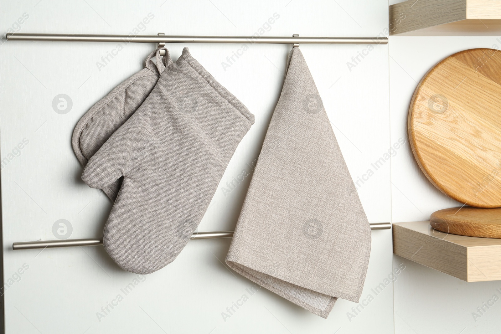 Photo of Oven glove, potholder and towel hanging on metal rack in kitchen