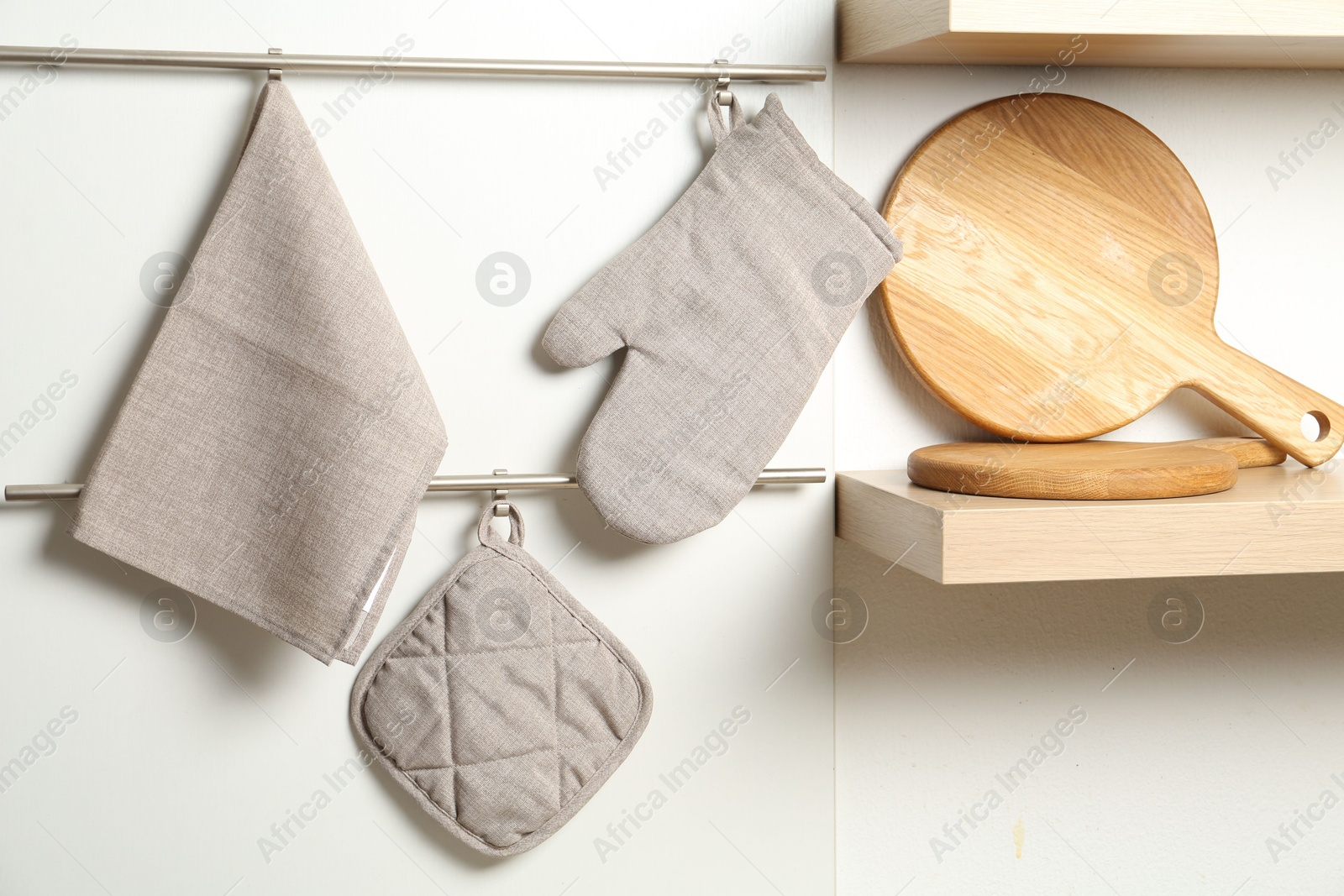 Photo of Oven glove, potholder and towel hanging on metal rack in kitchen