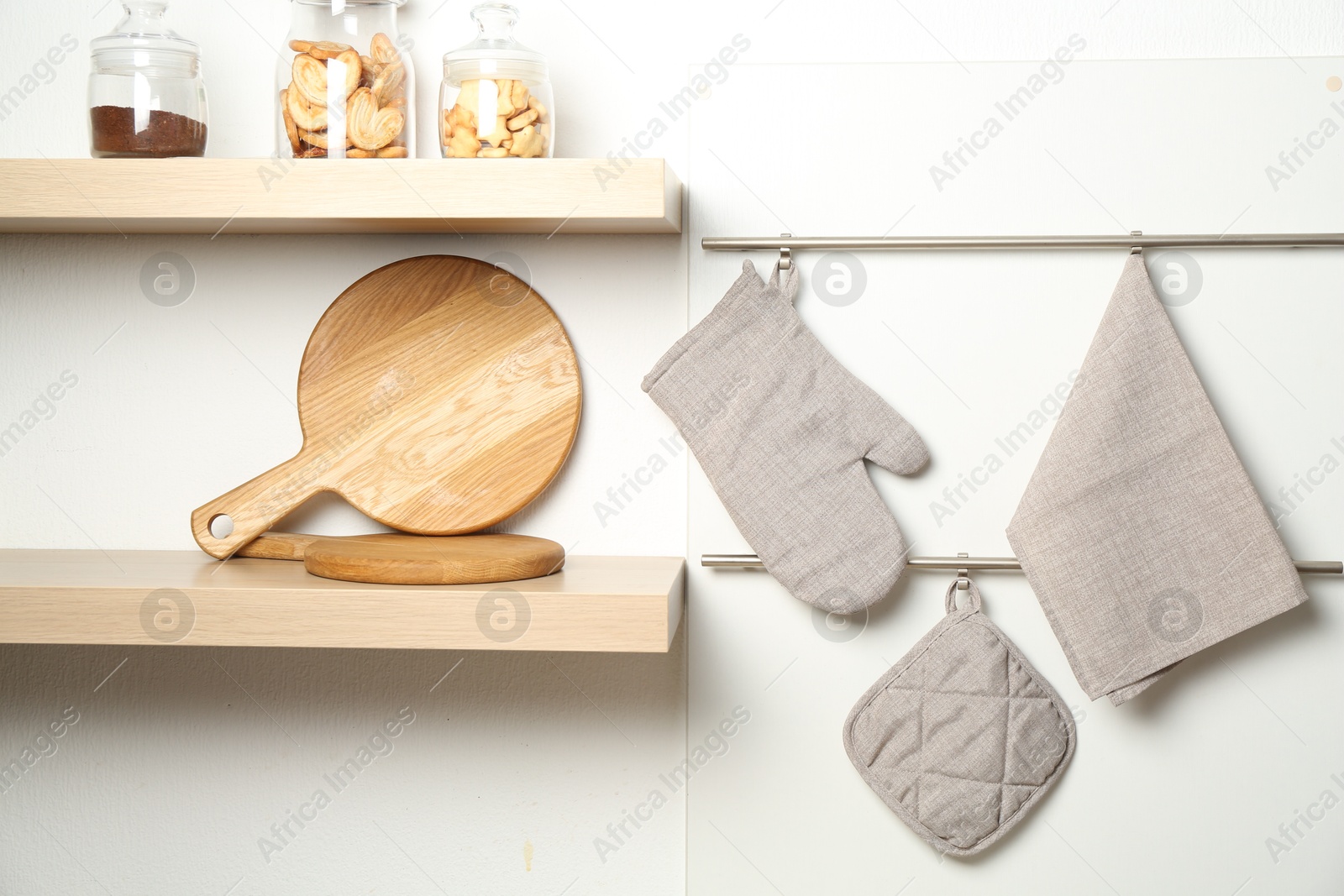 Photo of Oven glove, potholder and towel hanging on metal rack in kitchen
