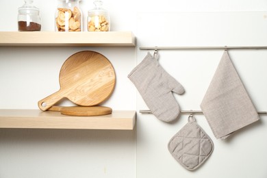 Photo of Oven glove, potholder and towel hanging on metal rack in kitchen
