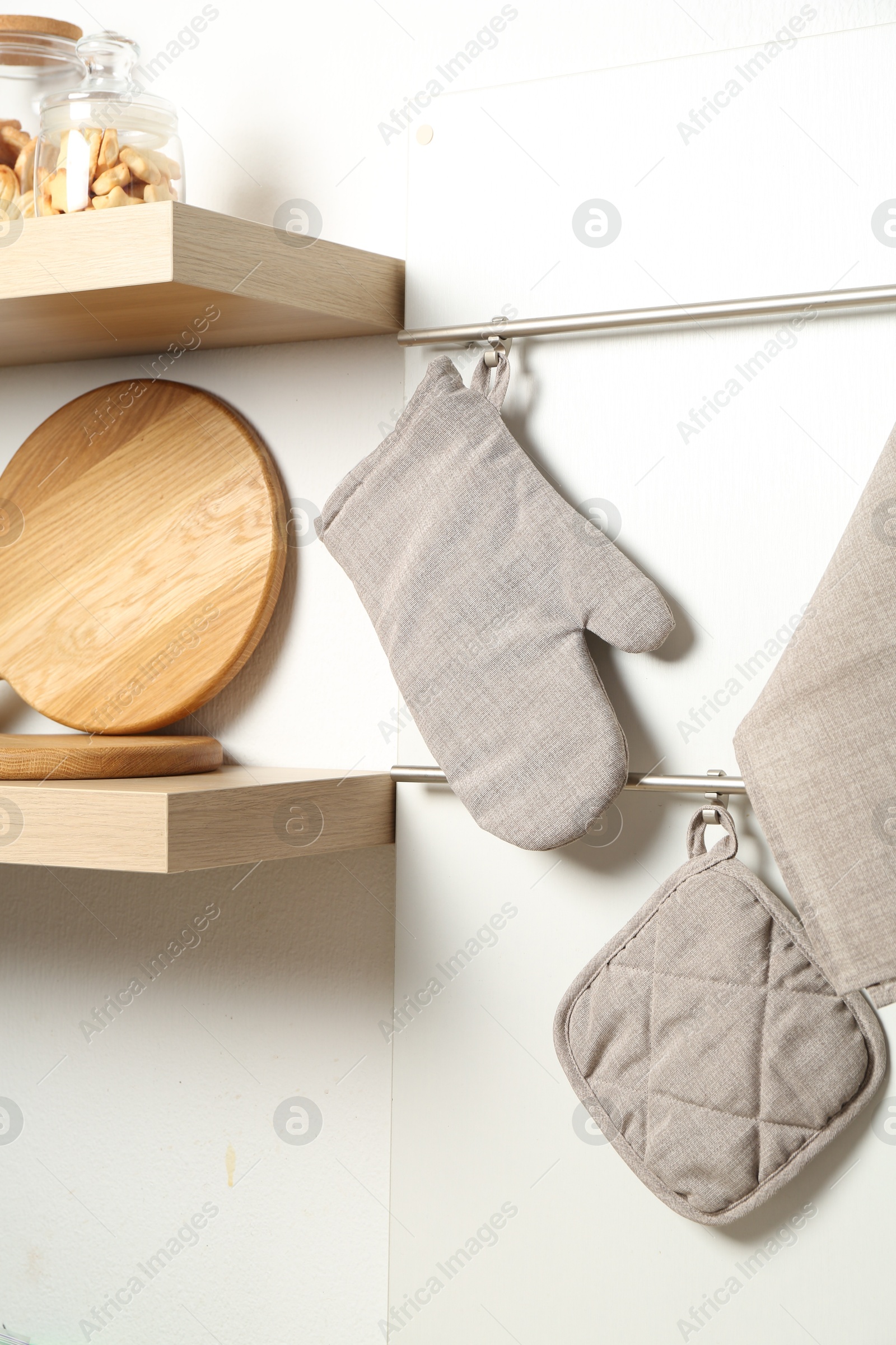 Oven glove, potholder and towel hanging on metal rack in kitchen Photo of Oven glove, potholder and towel hanging on metal rack in kitchen