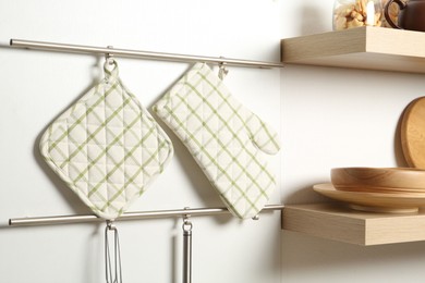 Photo of Oven glove and potholder hanging on metal rack in kitchen