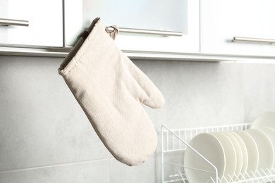 Photo of Oven glove hanging on handle of cabinet in kitchen