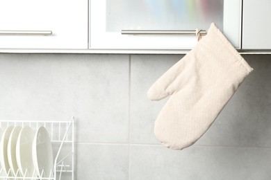 Photo of Oven glove hanging on handle of cabinet in kitchen