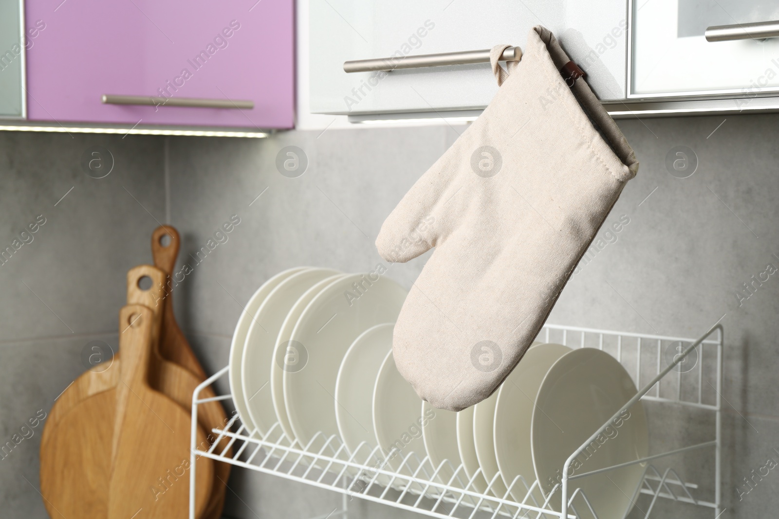 Photo of Oven glove hanging on handle of cabinet in kitchen