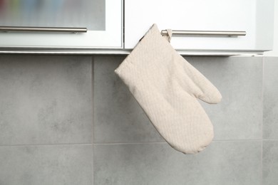 Photo of Oven glove hanging on handle of cabinet in kitchen
