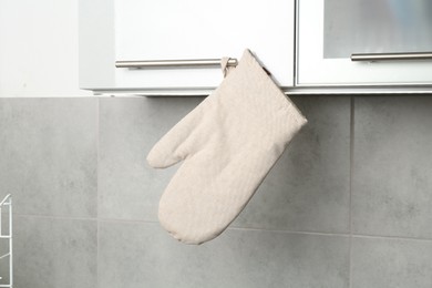 Photo of Oven glove hanging on handle of cabinet in kitchen