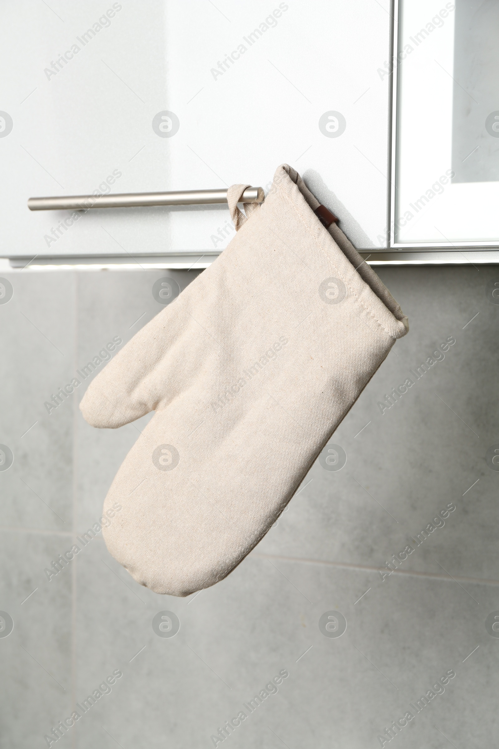 Photo of Oven glove hanging on handle of cabinet in kitchen