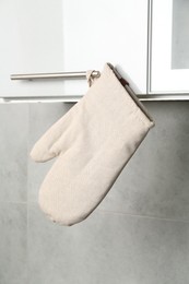 Photo of Oven glove hanging on handle of cabinet in kitchen