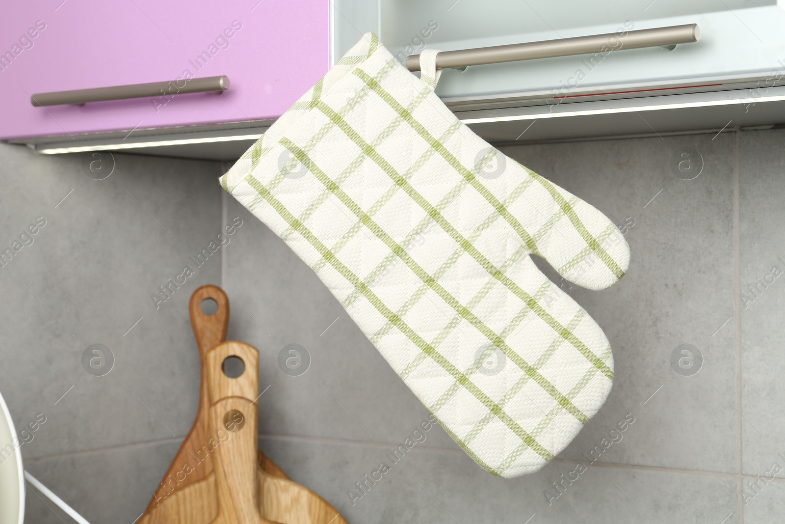 Photo of Oven glove hanging on handle of cabinet in kitchen