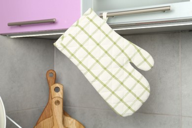 Photo of Oven glove hanging on handle of cabinet in kitchen