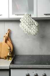Photo of Oven glove and potholder hanging on handle of cabinet in kitchen