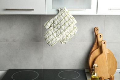 Photo of Oven glove and potholder hanging on handle of cabinet in kitchen