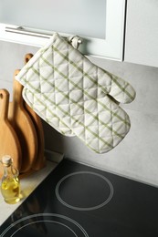 Photo of Oven glove and potholder hanging on handle of cabinet in kitchen