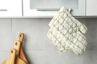 Photo of Oven glove and potholder hanging on handle of cabinet in kitchen