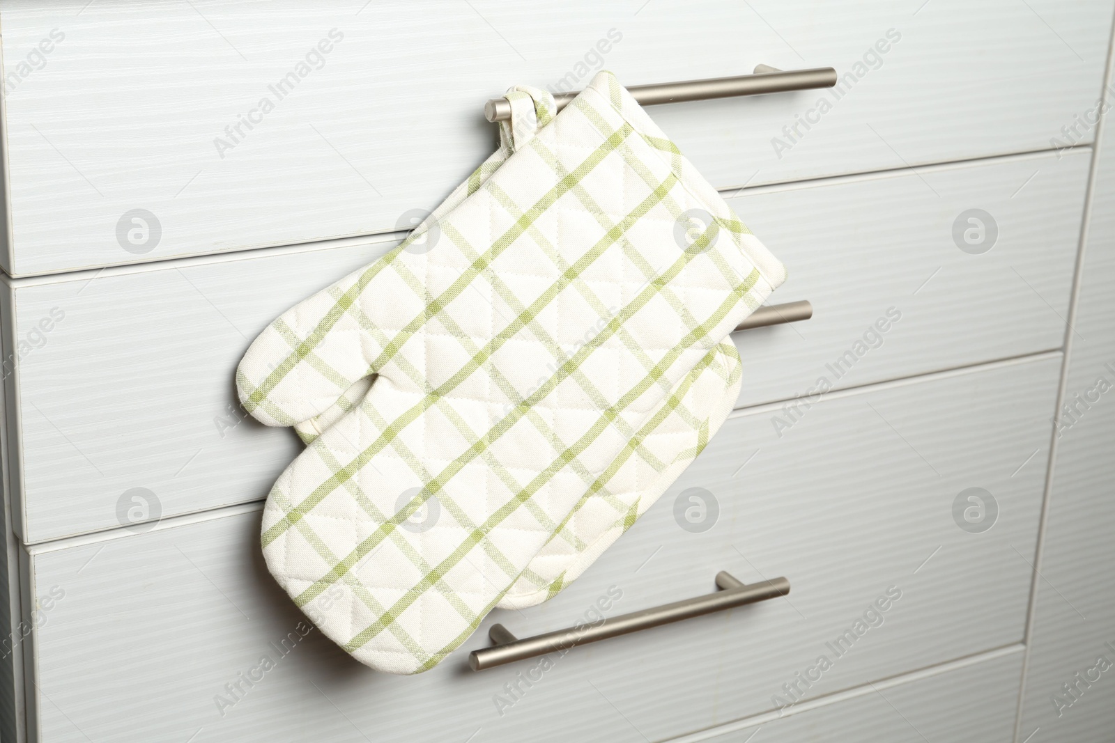 Oven glove and potholder hanging on handle of cabinet in kitchen Photo of Oven glove and potholder hanging on handle of cabinet in kitchen