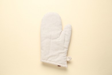 Photo of One oven glove on beige background, top view