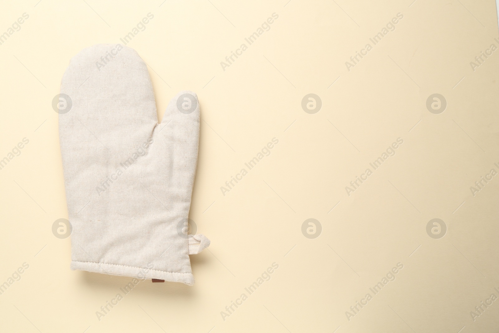 Photo of One oven glove on beige background, top view. Space for text