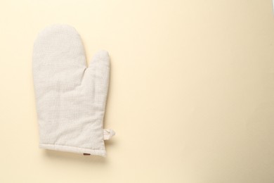 Photo of One oven glove on beige background, top view. Space for text