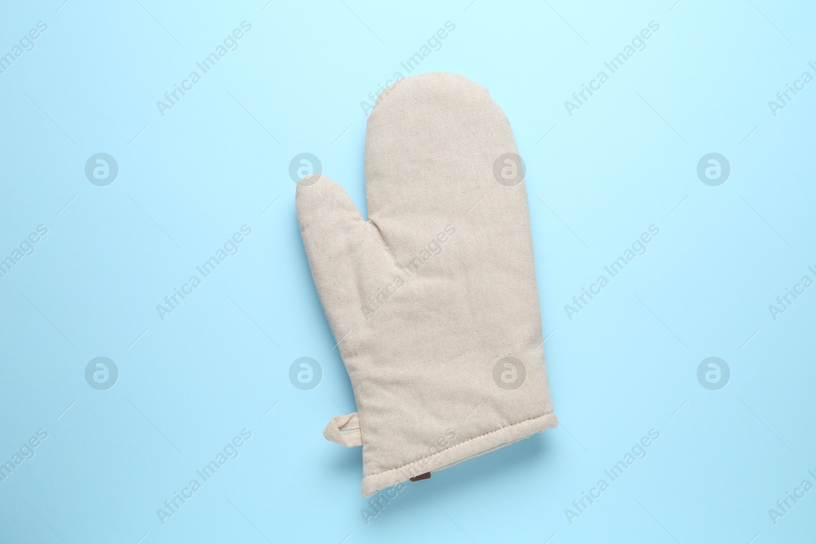 Photo of One oven glove on light blue background, top view
