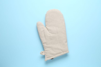 Photo of One oven glove on light blue background, top view