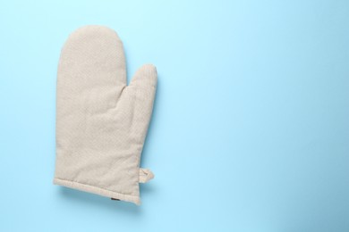 Photo of One oven glove on light blue background, top view. Space for text