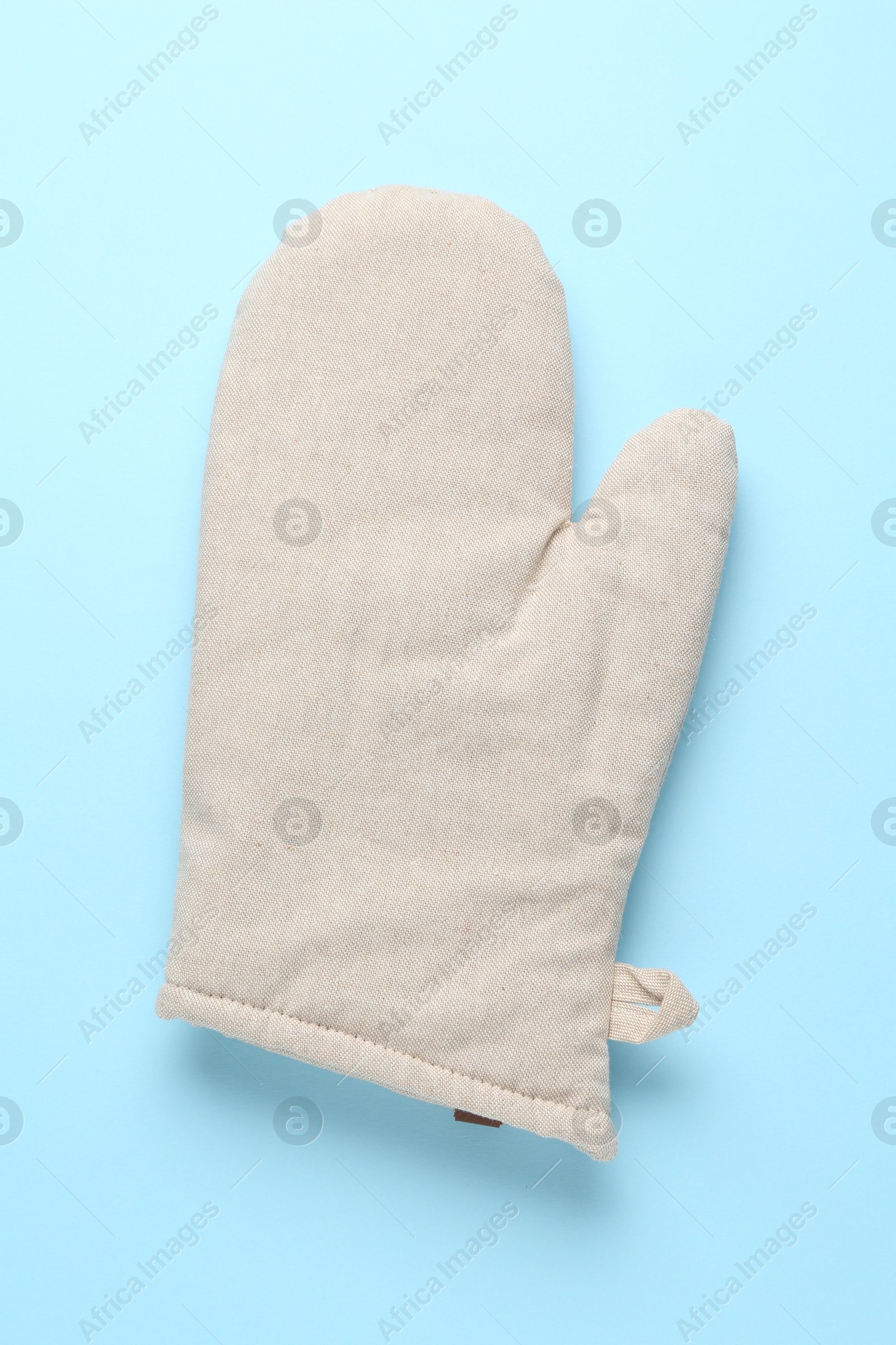 Photo of One oven glove on light blue background, top view