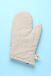 Photo of One oven glove on light blue background, top view