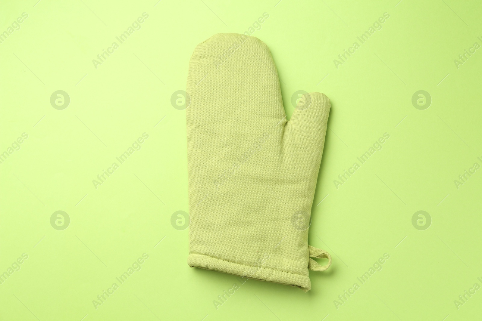 Photo of One oven glove on green background, top view