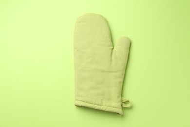 Photo of One oven glove on green background, top view