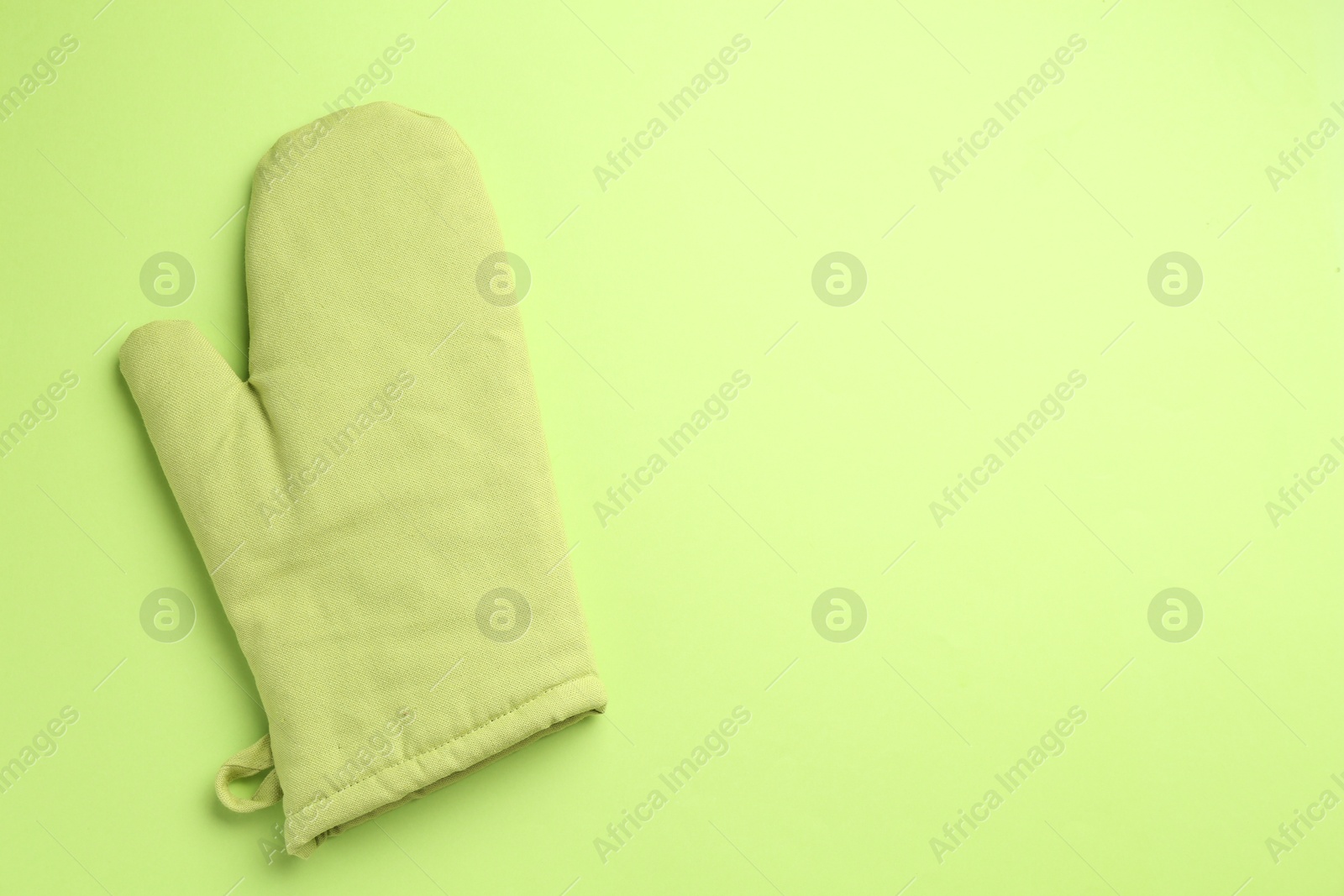 Photo of One oven glove on green background, top view. Space for text