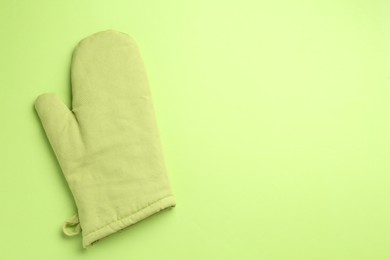 Photo of One oven glove on green background, top view. Space for text