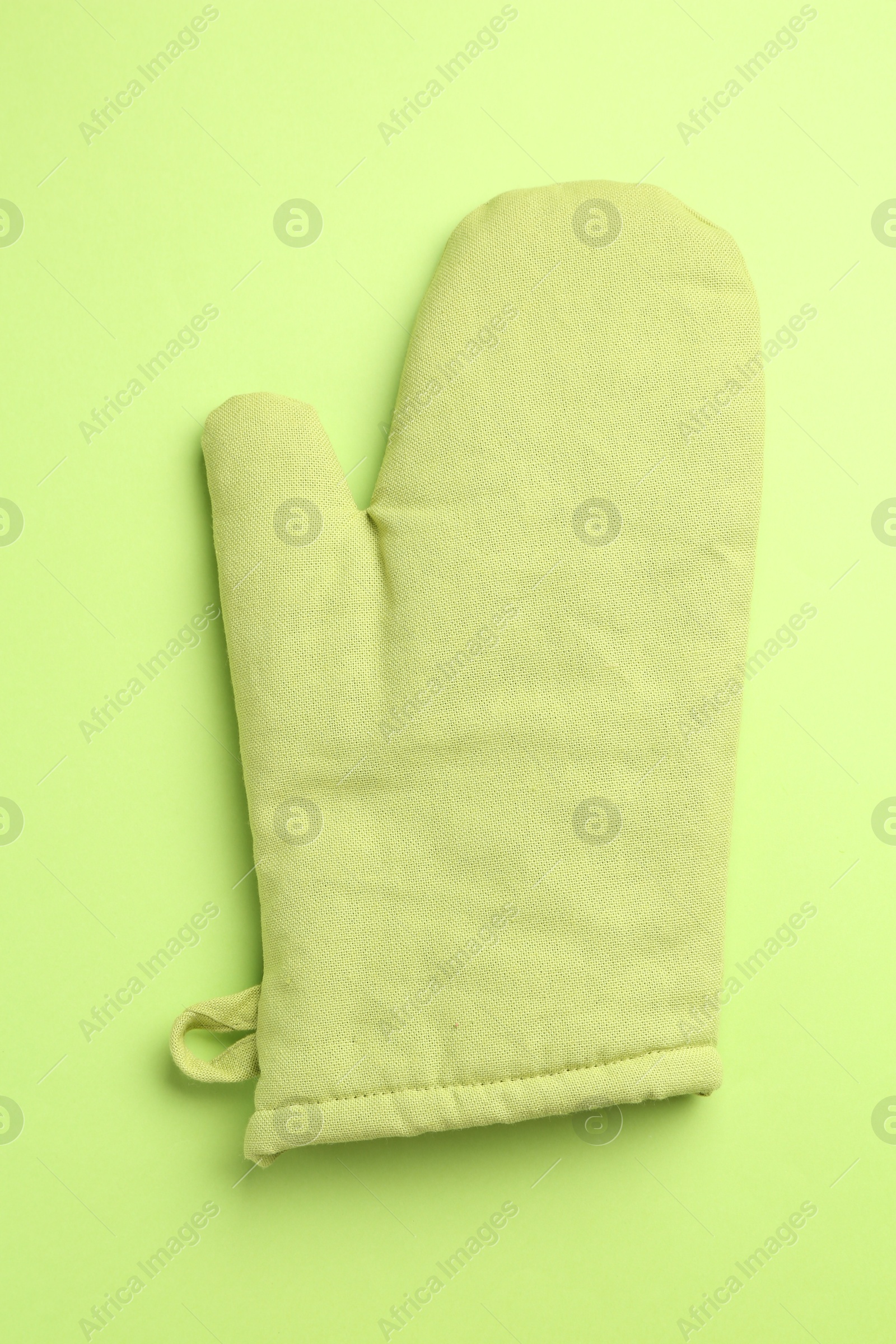 Photo of One oven glove on green background, top view