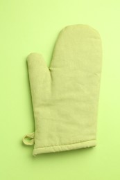 Photo of One oven glove on green background, top view