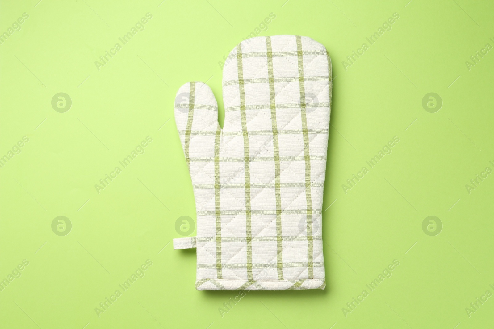 Photo of One oven glove on green background, top view