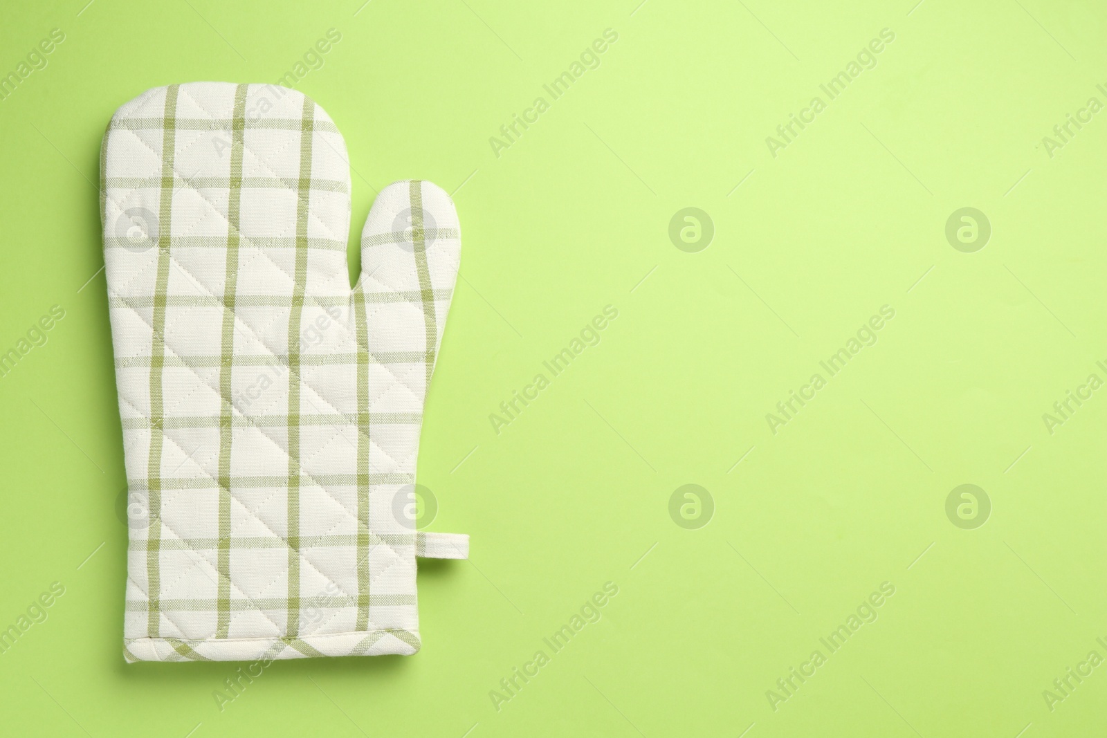 One oven glove on green background, top view. Space for text Photo of One oven glove on green background, top view. Space for text